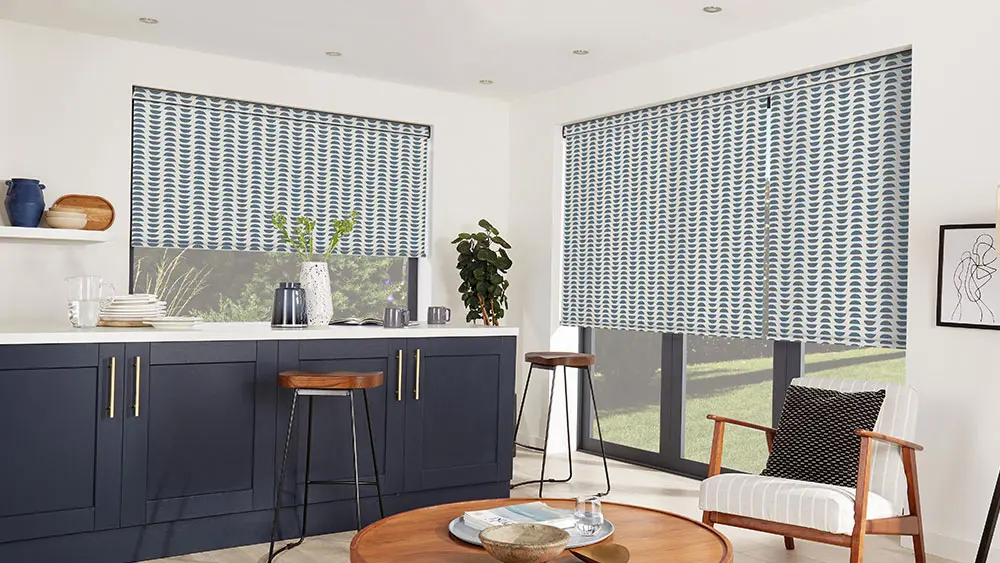 Patterned blue roller blinds in a stylish modern kitchen with navy cabinetry and a breakfast bar
